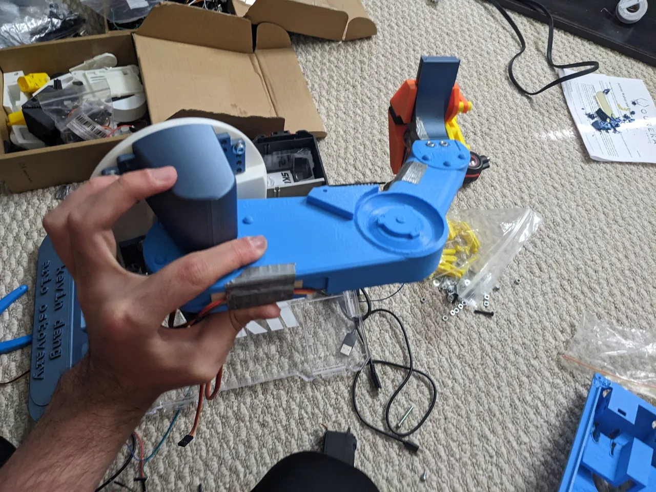 The blue articulated arm being held during assembly, with wires and gripper parts visible