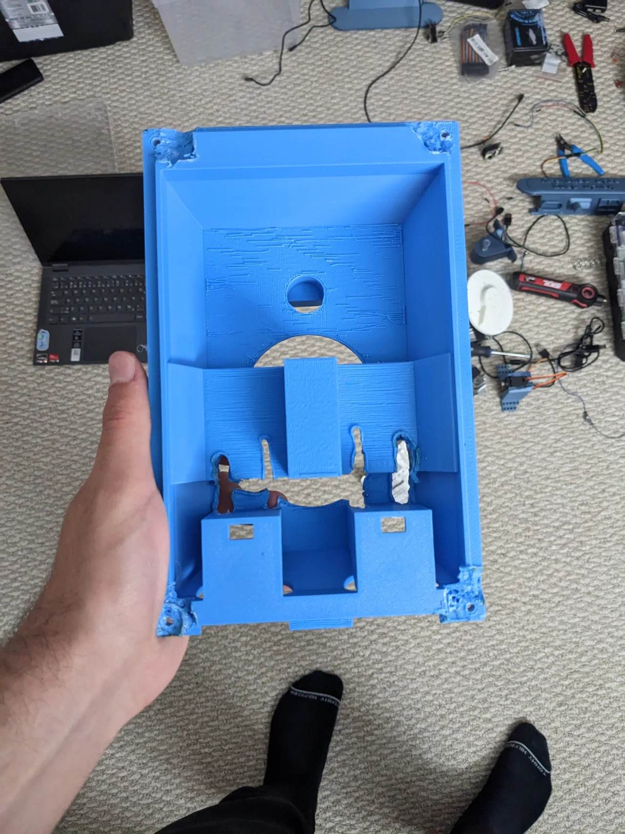 The blue printed base shell held open to show its internal mounting features