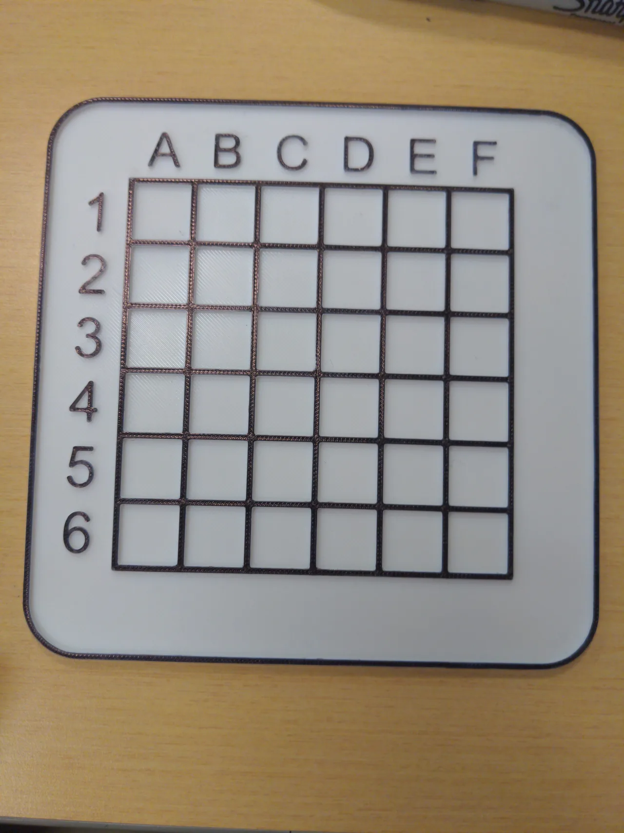 An empty 3D-printed six-by-six board with rows numbered one to six and columns labelled A to F