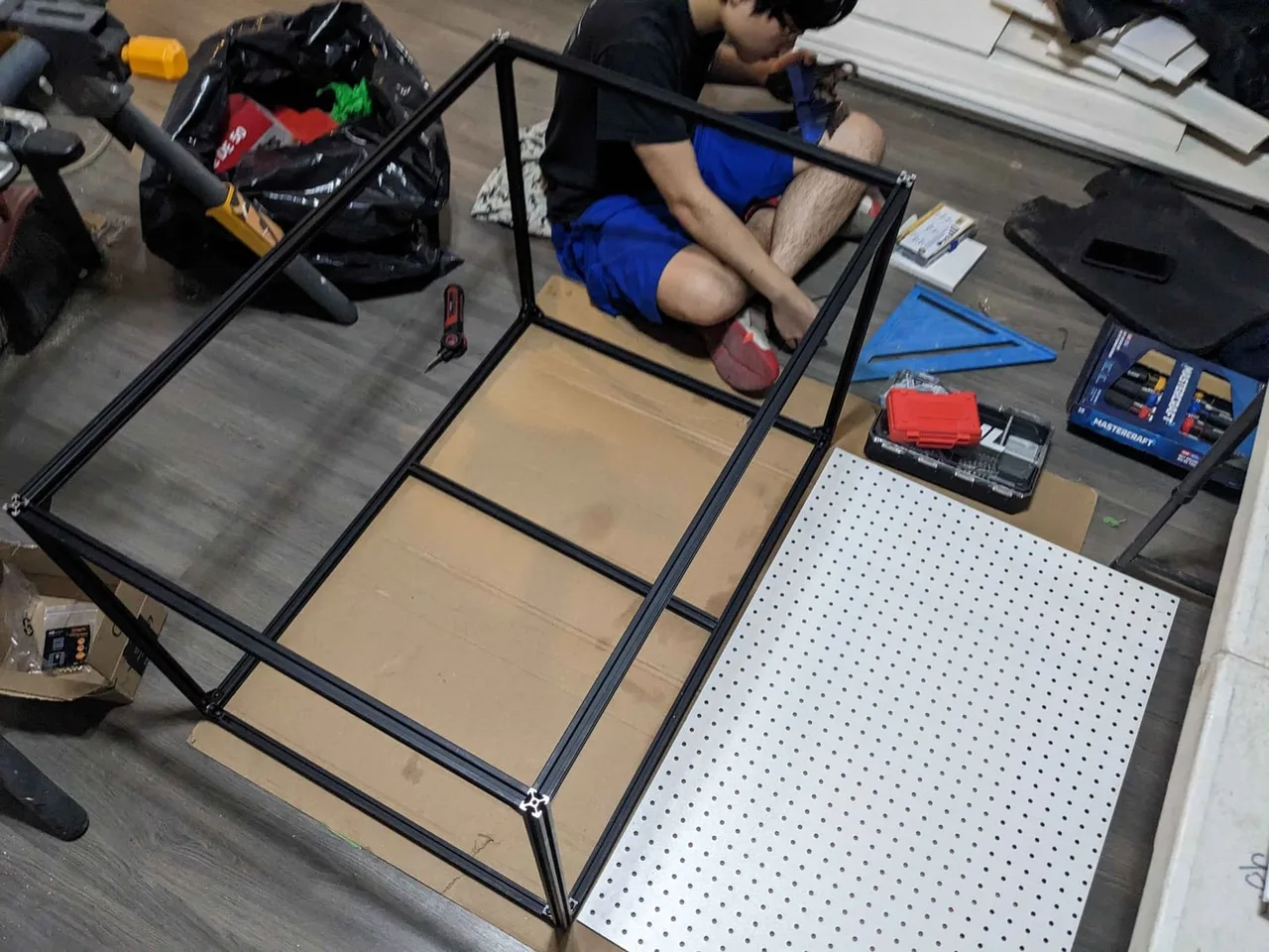 The 2020 aluminium frame assembled on the floor beside the pegboard