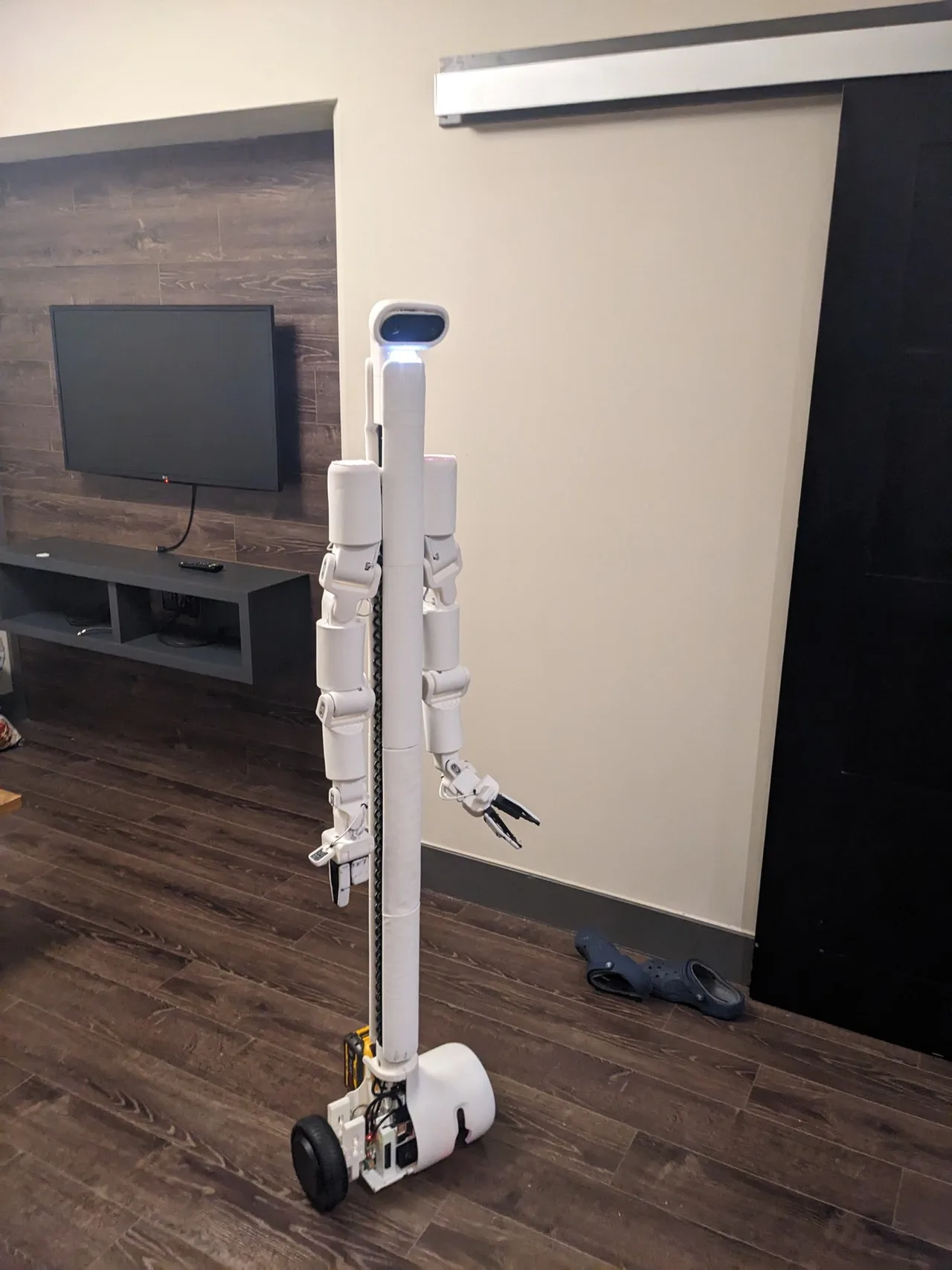 Full BracketBot in the apartment, showing the stereo head cameras, two arms and wheeled base