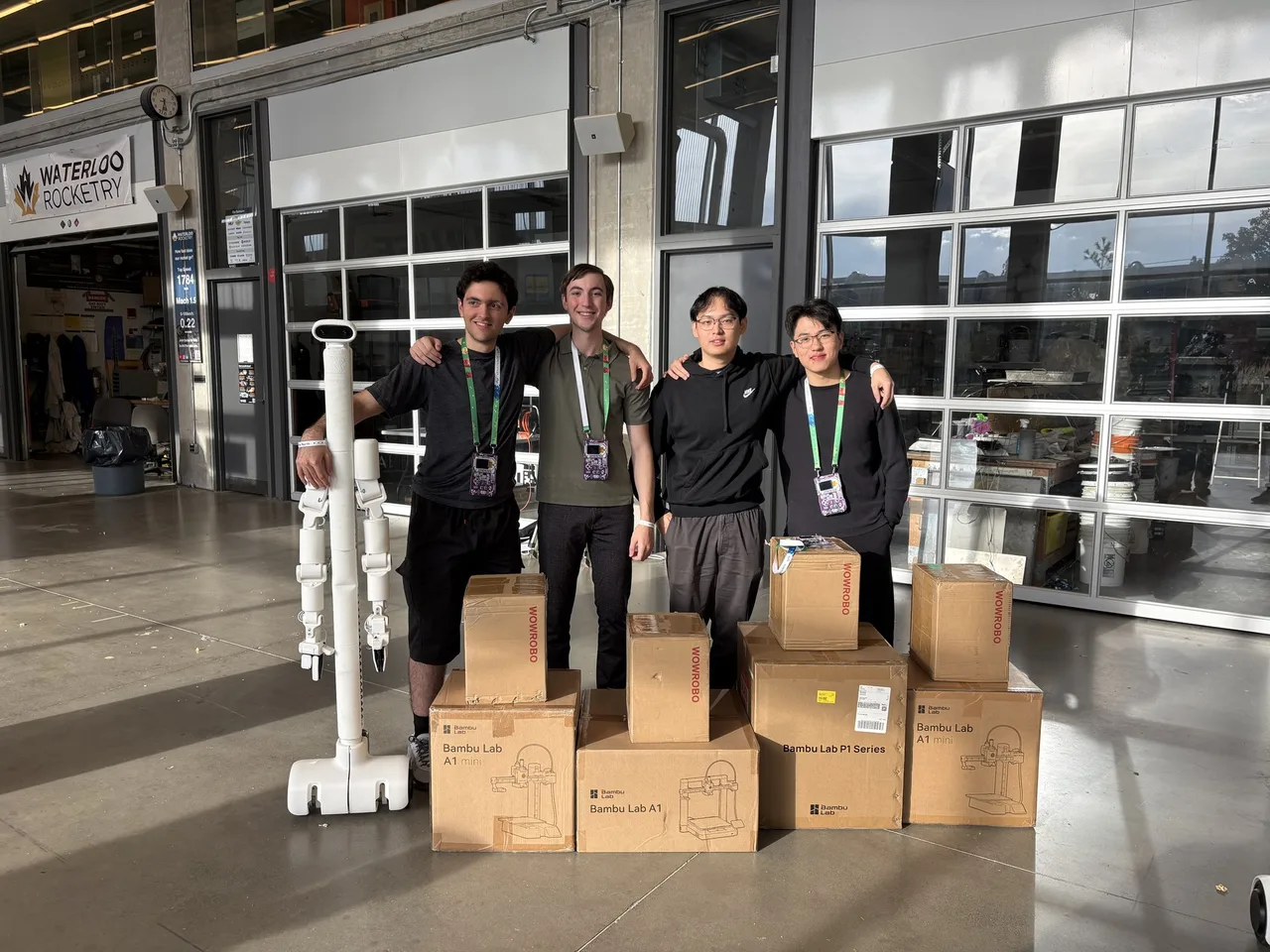 The project team beside a BracketBot and their boxed prizes at Hack the North